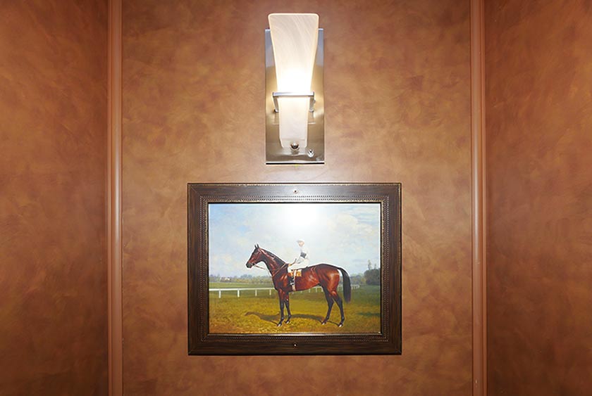 WALL SCONCE LIGHTING AND FRAMED ARTWORK IN EACH BATHROOM STALL