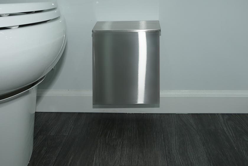 COVERED TRASH RECEPTACLE NEAR PORCELAIN TOILET