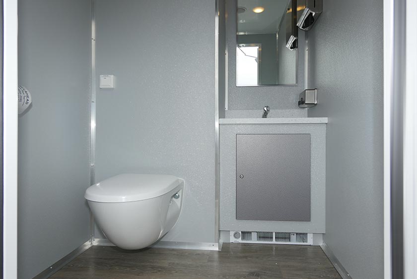 TOILET, VANITY WITH SINK AND MIRROR INSIDE THE FREEDOM RESTROOM TRAILER